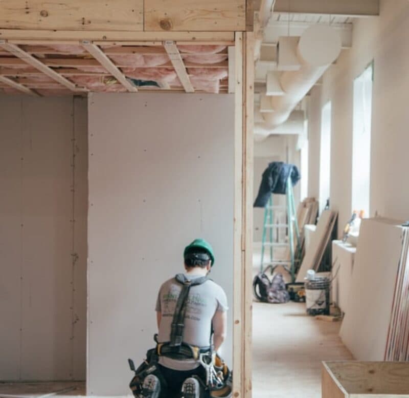 Builder performing essential building maintenance in unfinished commercial space