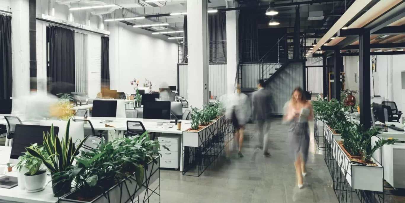 Long exposure shot of office workers walking through open plan office environment